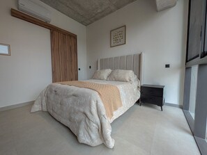 A bedroom with a bed, a nightstand, a wooden wardrobe, and a framed picture on the wall. - Avmx Living 5A 1 bed (Guadalajara)