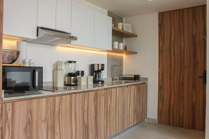 A modern kitchen with a wooden countertop, a built-in microwave, a coffee maker, and a sink. - Avmx Living 5A 1 bed (Guadalajara)