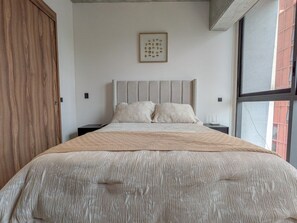 Ein Schlafzimmer mit einem Bett, einem Holzschrank, einem gerahmten Kunstwerk an der Wand und einem Fenster.