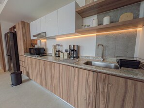 A modern kitchen with a wooden cabinet design, a stainless steel sink, and a coffee maker.