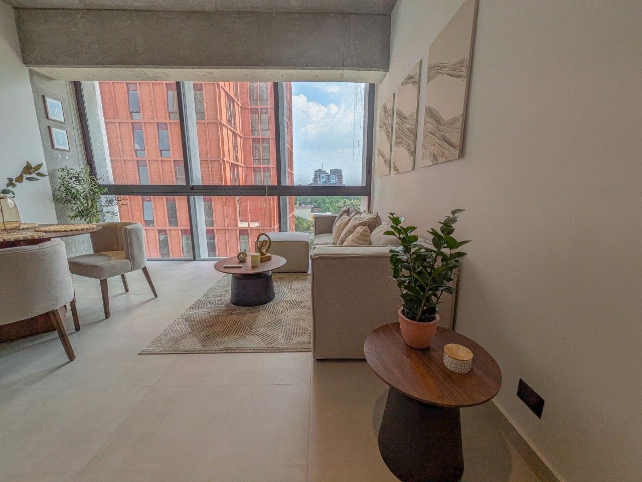 Een moderne woonkamer met een bank, fauteuils, een bijzettafeltje en een potplant.