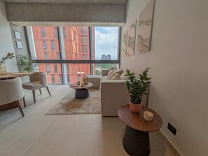 A modern living room with a sofa, chairs, a coffee table, and a potted plant. - Avmx Living 5A 1 bed (Guadalajara)