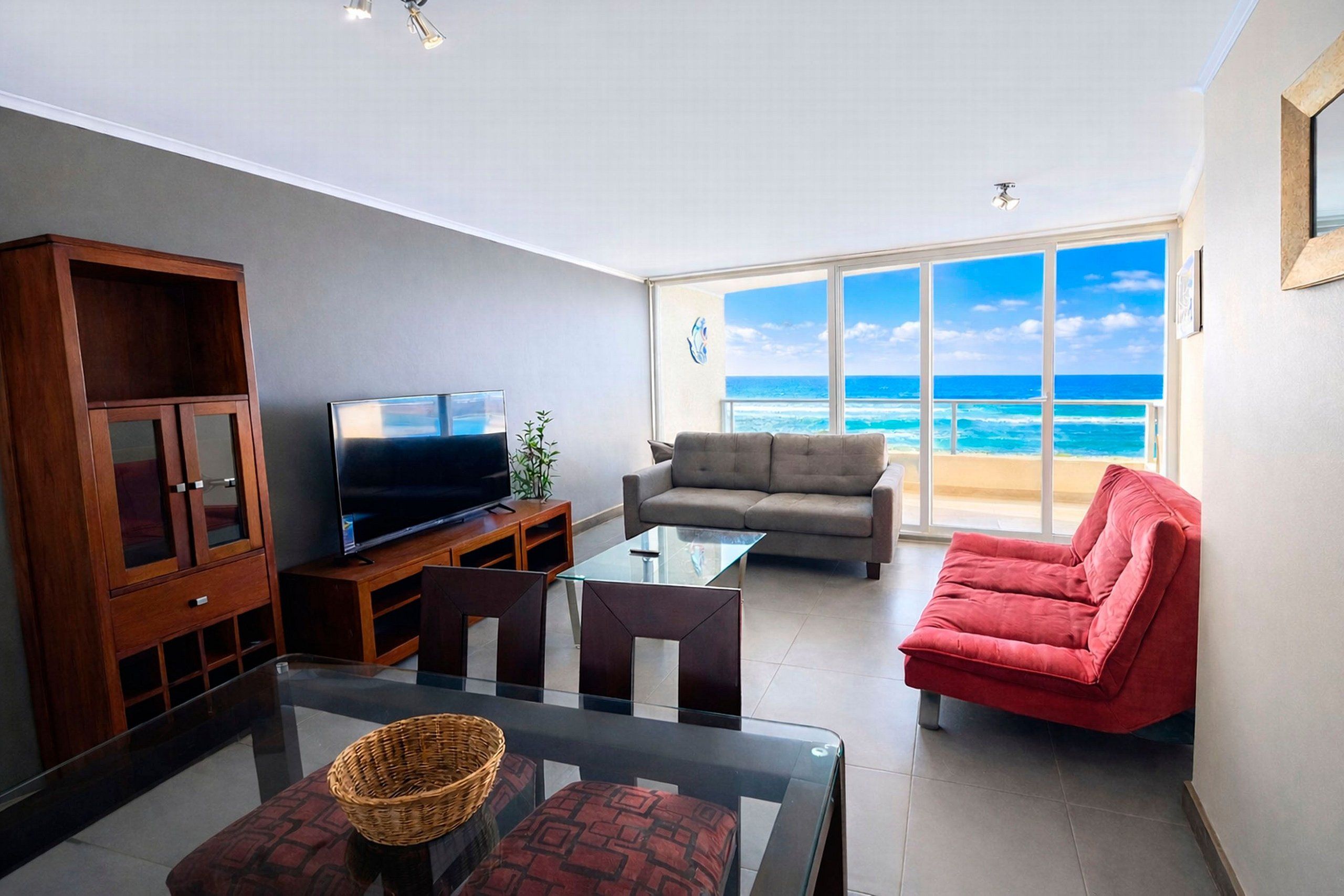 A living room with a television, sofa, and a glass table.