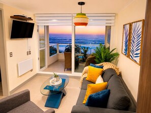 Ein Wohnzimmer mit einer Couch, einem Couchtisch und Meerblick durch eine Schiebetür.