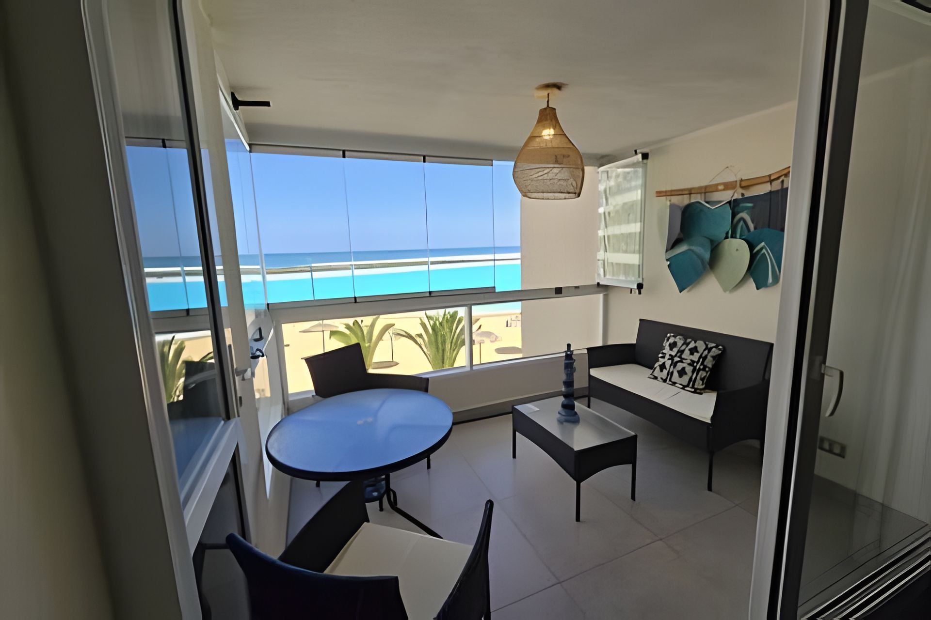 A balcony with a table and chairs, a sofa, and a hanging light fixture.