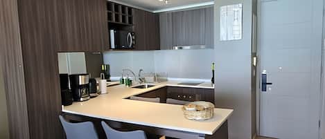 A modern kitchen with a central island, built-in appliances, and a dining area with chairs.