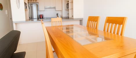 A modern kitchen with white cabinets, a stainless steel refrigerator, and a coffee maker on the counter.
