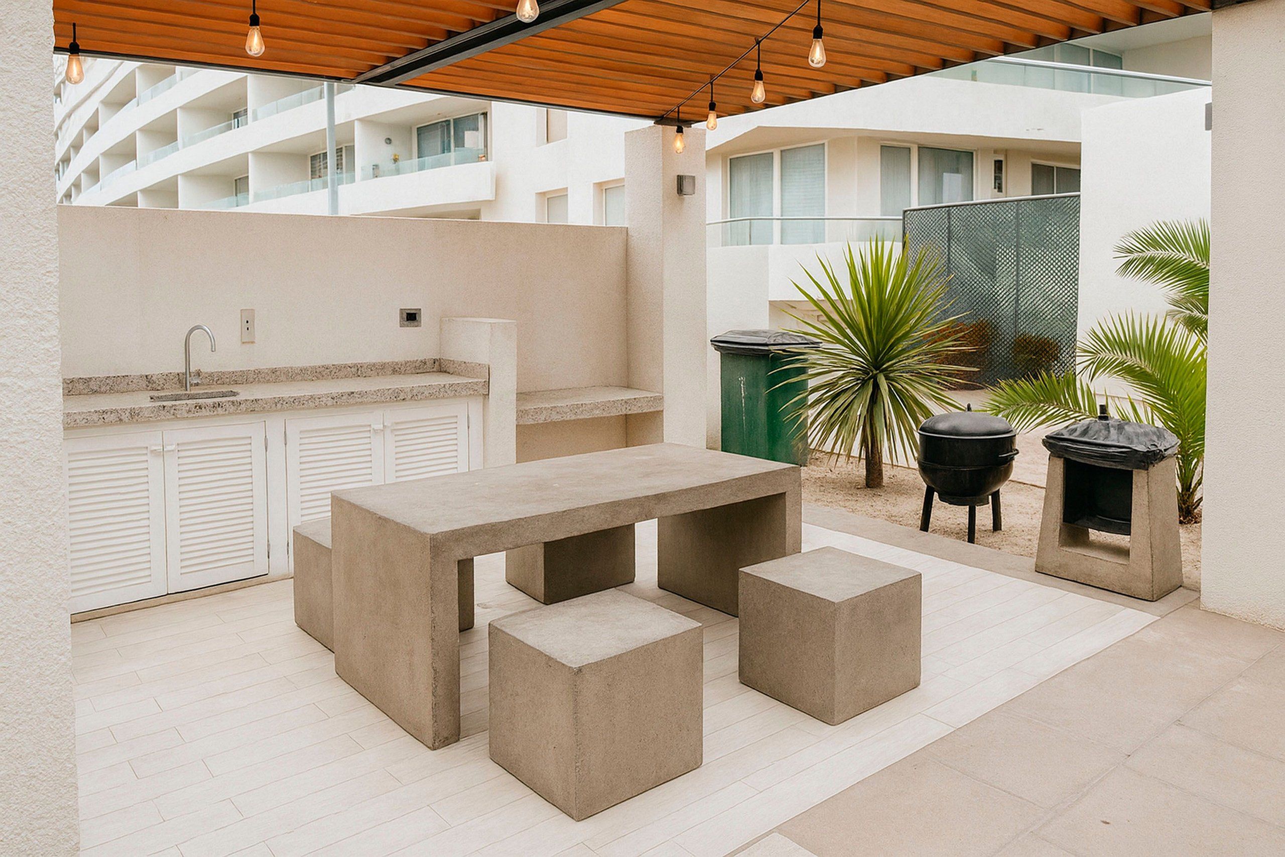 An outdoor patio with a concrete table and benches, a sink, and a barbecue grill.