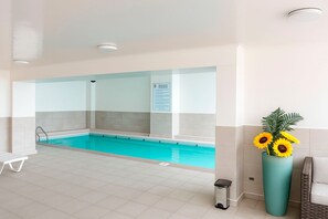 Ein Schwimmbecken mit klarem, blauem Wasser, einem weißen Fliesenboden und einem Schild an der Wand.