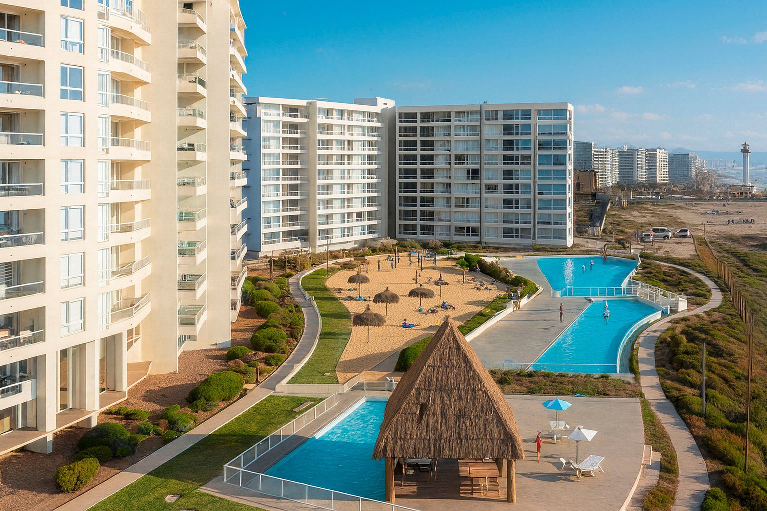 Ein Resort mit mehreren Schwimmpools, einem Strandbereich und hoch aufragenden Gebäuden.