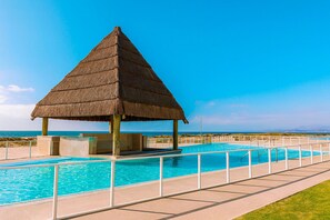 Una construcció amb teulada de palla sobre una piscina amb vista clara a l'oceà.