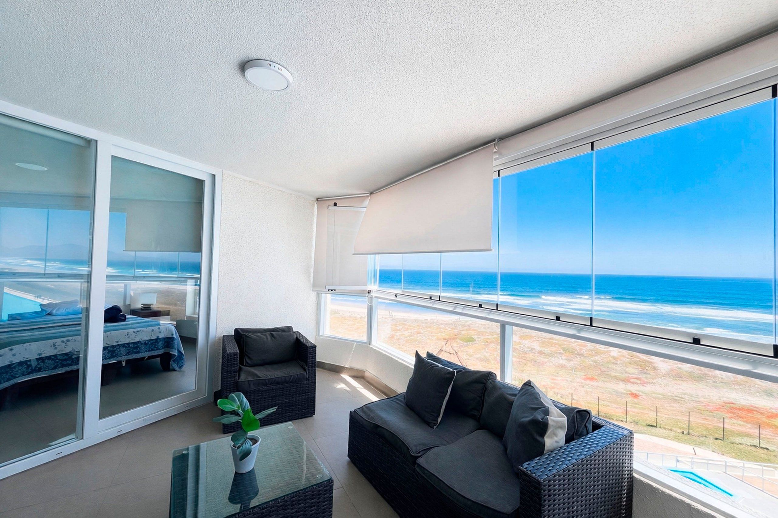Un balcone con vista sull'oceano, un letto, un divano e un tavolino con una pianta.