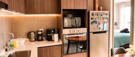 A modern kitchen with a built-in microwave, coffee maker, and a small dining area with a table and chairs.