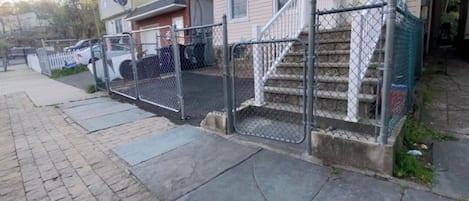 Un edificio residencial con porche delantero, escalera y entrada cercada.