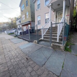 A residential building with a front porch, a staircase, and a fenced driveway. - Master bedroom with private bath! (Paterson)