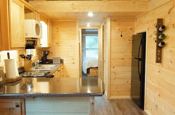 A compact kitchen with wooden walls, a refrigerator, and a microwave. - See Rock Log Cabin — With a view of See Rocks Arch (Stanton)