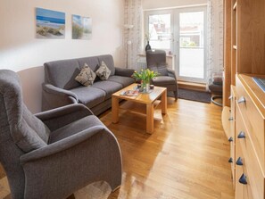 A modern living room with a grey sofa, a wooden coffee table, and a grey armchair. - Holiday Apartment in Norderney With Wi-fi (Norderney)