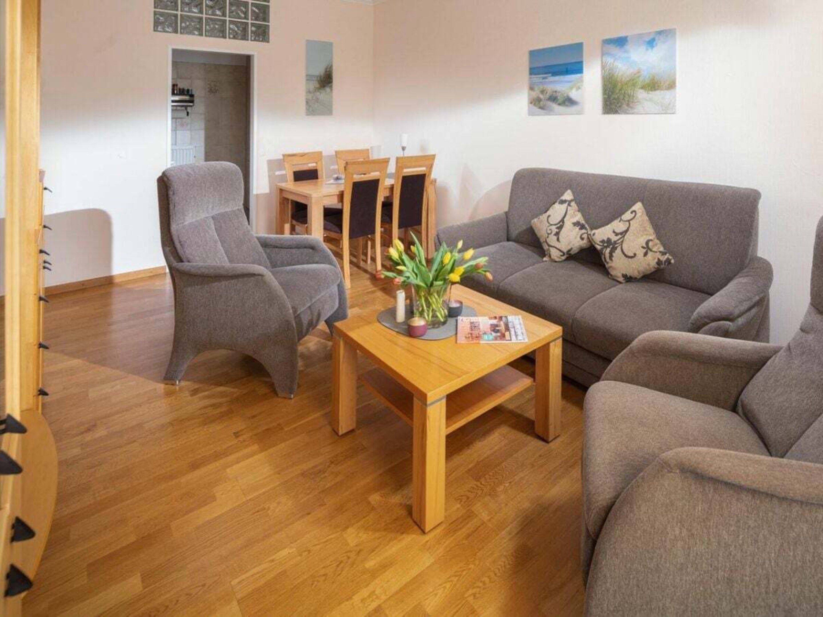 Ein modernes Wohnzimmer mit einem grauen Sofa, einem grauen Sessel und einem Holztisch.