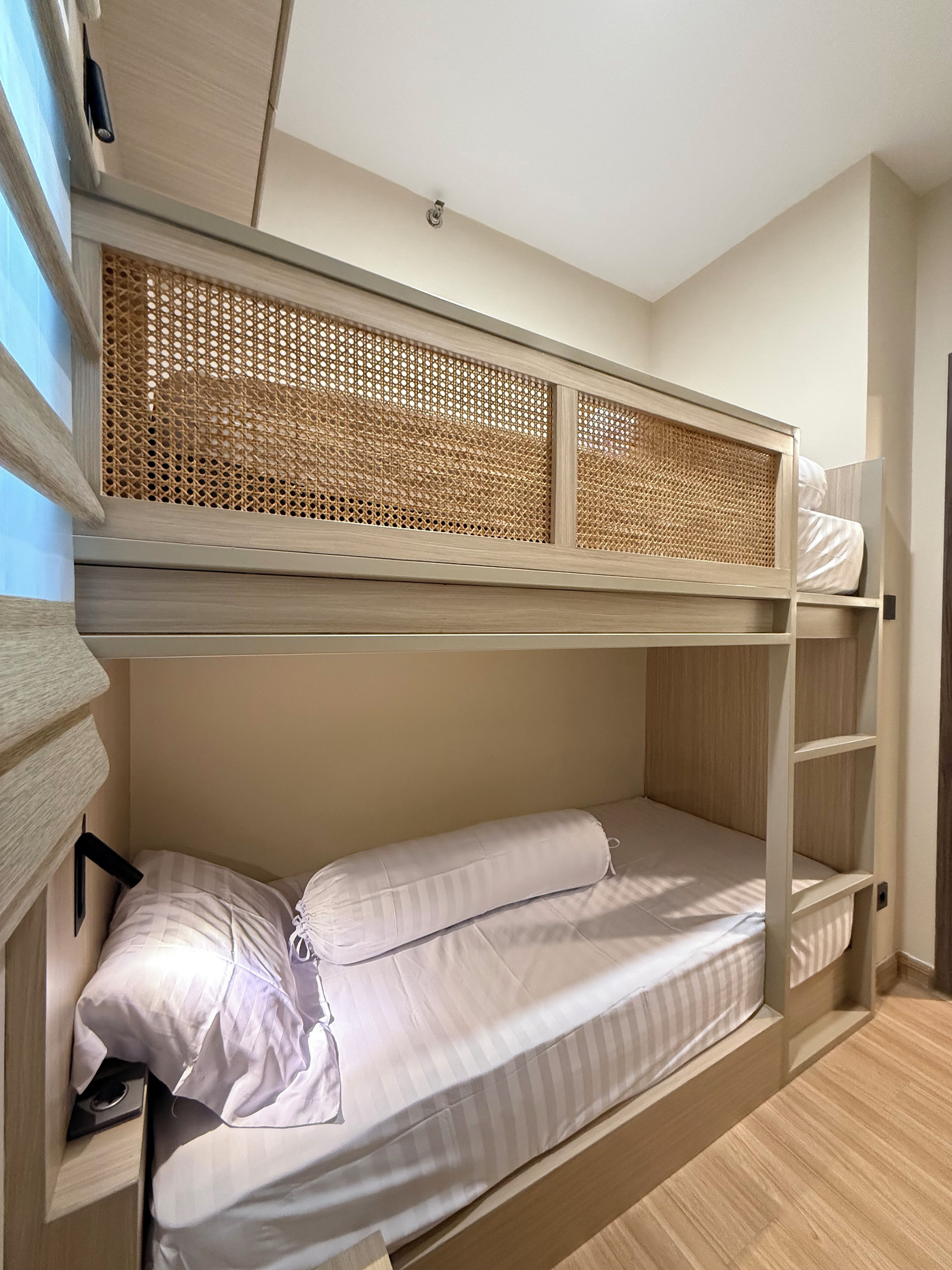 A bunk bed with a woven headboard, a single bed below, and a small shelf.