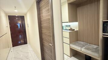 A hallway with a marble floor, a wooden door, and a mirrored wall reflecting a kitchen area.