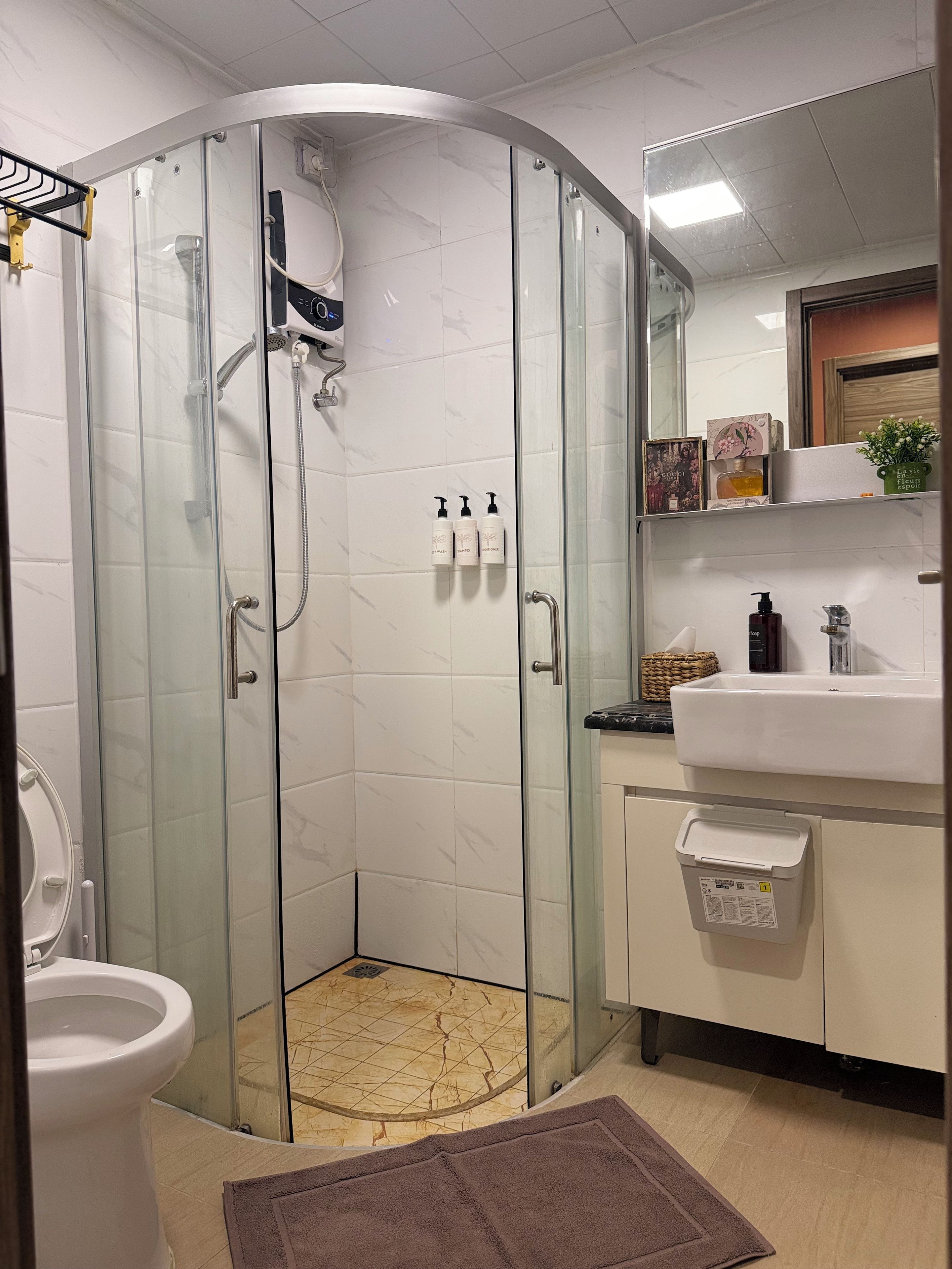 A bathroom with a glass-enclosed shower, a white sink, and a mirror above it.