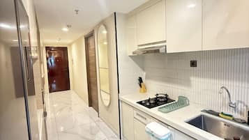 A modern kitchen with white cabinetry, a stainless steel sink, and a marble floor.
