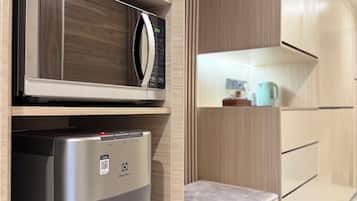 A compact kitchenette with a microwave, water dispenser, and a small countertop.