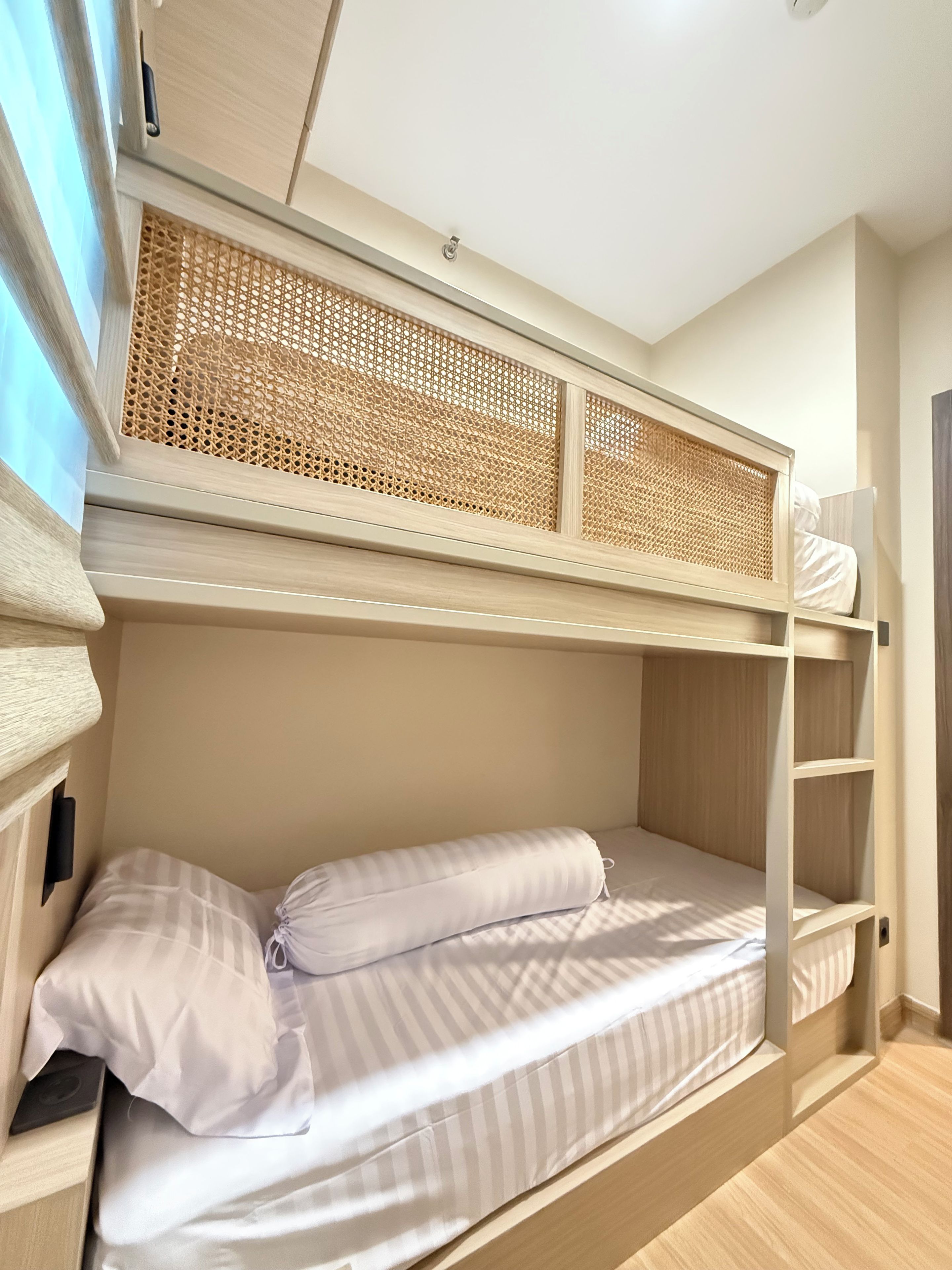 A bunk bed with a woven headboard, a bedside table, and a wall-mounted shelf.