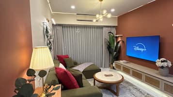 A modern living room with a sofa, a coffee table, a TV, and a lamp.