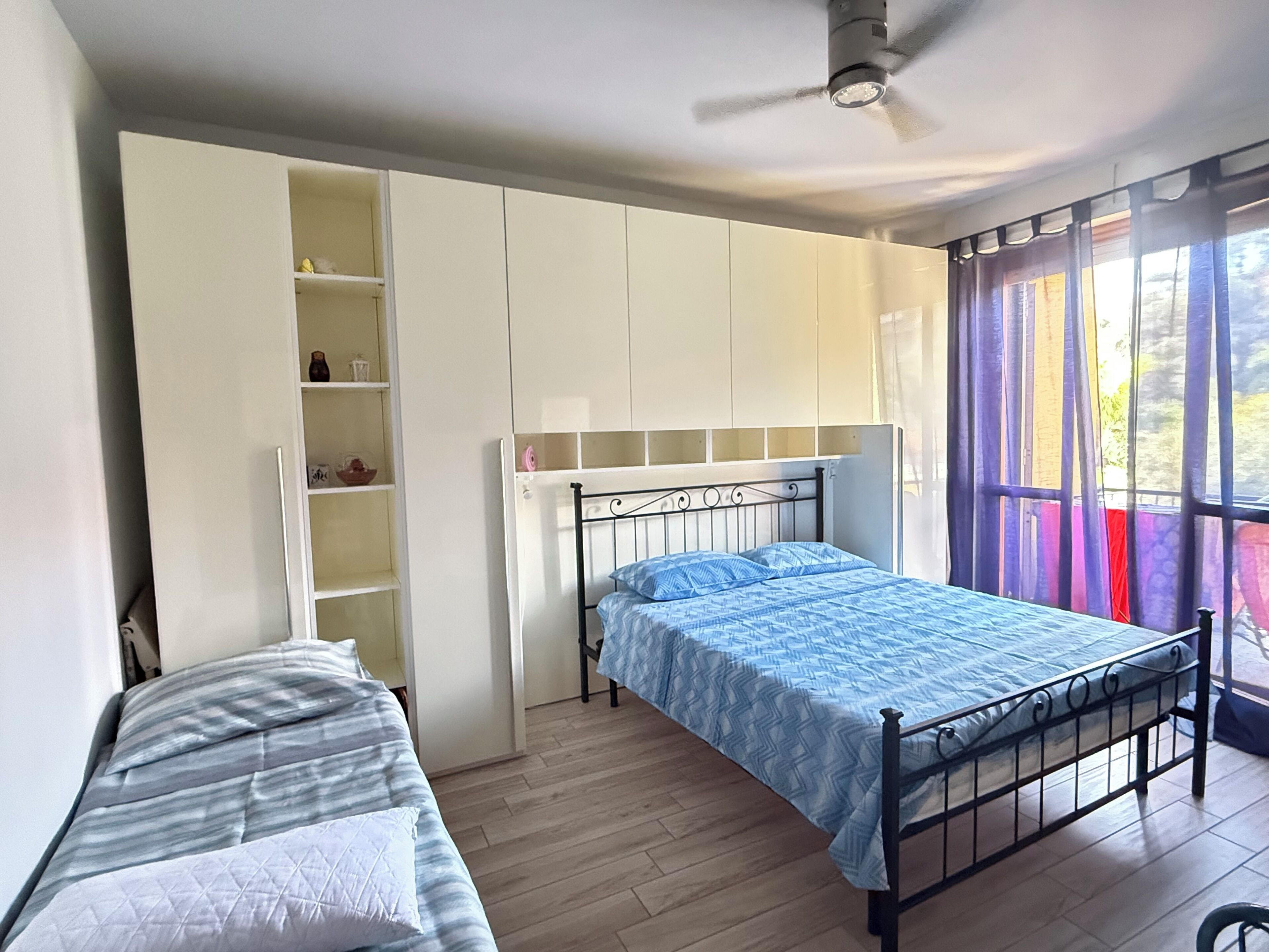 A bedroom with a single bed, a wardrobe, and a window with curtains.