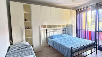 A bedroom with a single bed, a wardrobe, and a window with curtains.