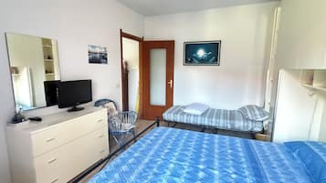 Una camera da letto con un letto, una cassettiera, una televisione, una sedia e una porta.