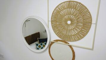A wall with a circular mirror, a woven wall art piece, and a woven placemat.
