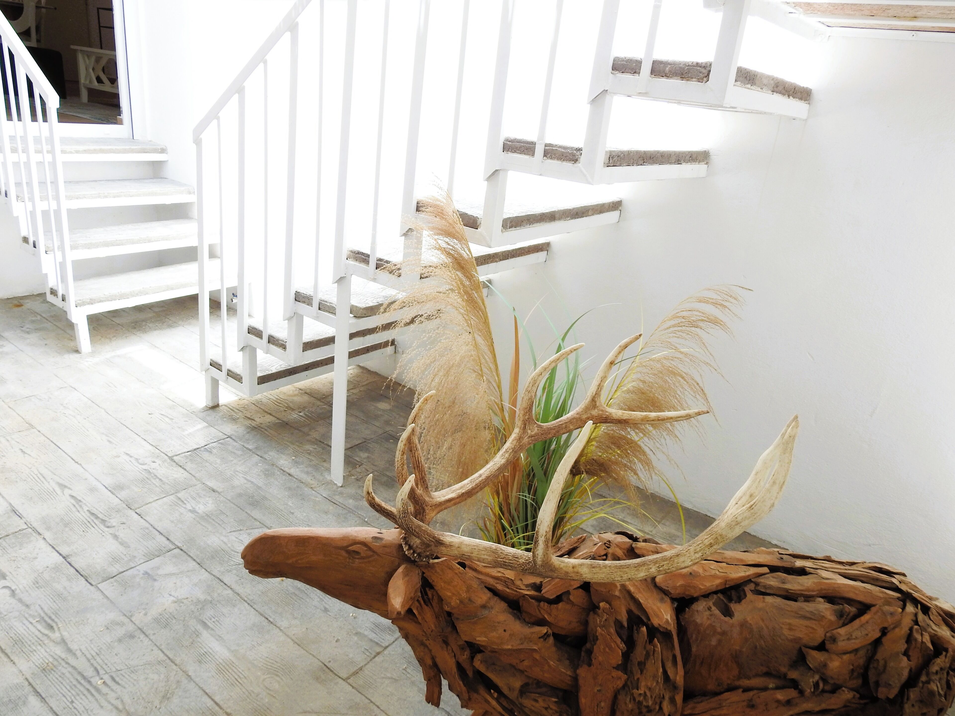Una escalera con barandas blancas y una decoración rústica de astas en el suelo.