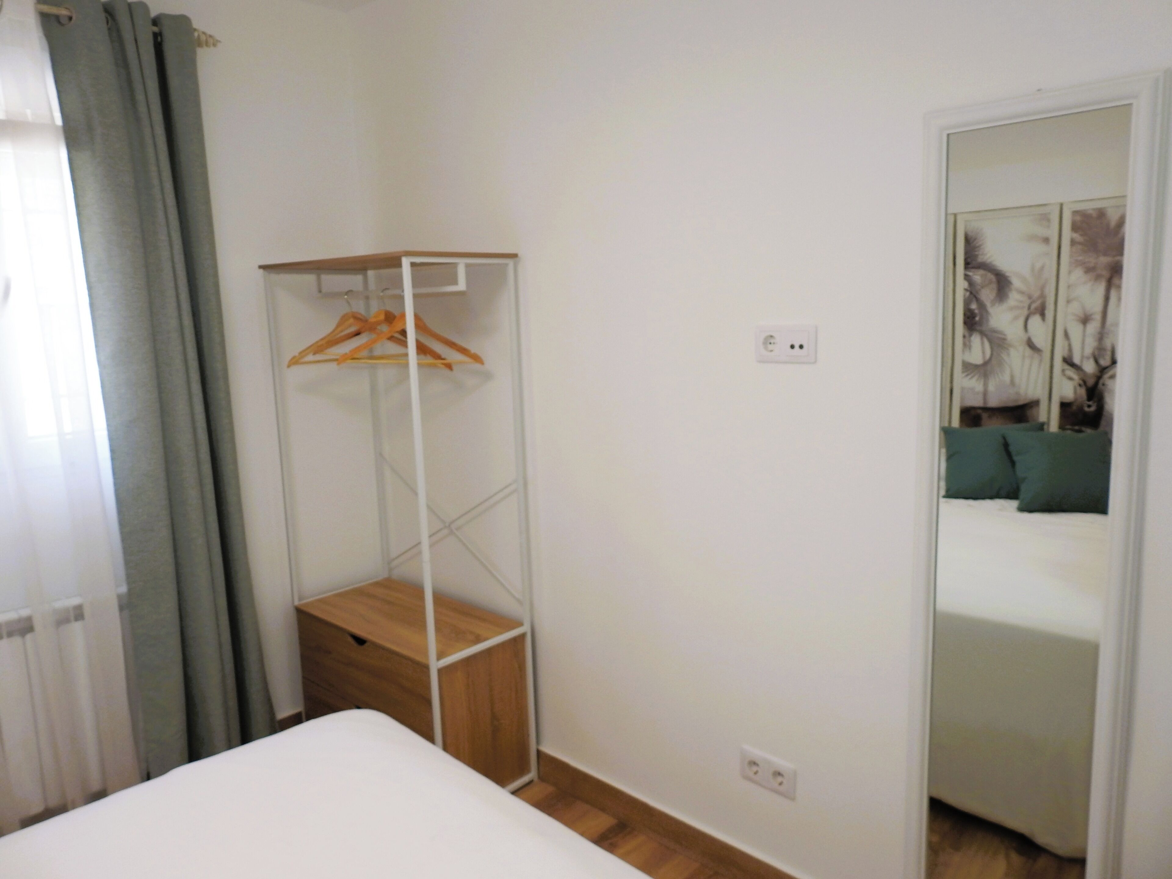 Un dormitorio con cama, armario y espejo que refleja una cama con almohadas.