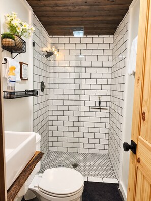 A bathroom with a shower, toilet, and a wooden vanity. - Musky Point Lake House (Mercer)