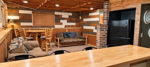A cozy room with a wooden dining table, chairs, a sofa, and a black refrigerator. - Musky Point Lake House (Mercer)