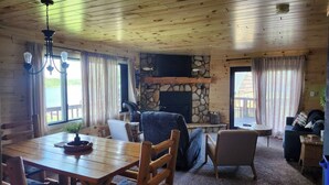 Un intérieur en bois avec une cheminée, une table à manger et un coin salon.