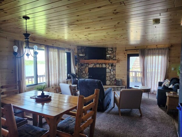 A wooden interior with a fireplace, dining table, and seating area.