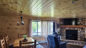Un intérieur en bois comprenant une table à manger, des chaises, un canapé et une cheminée en pierre.