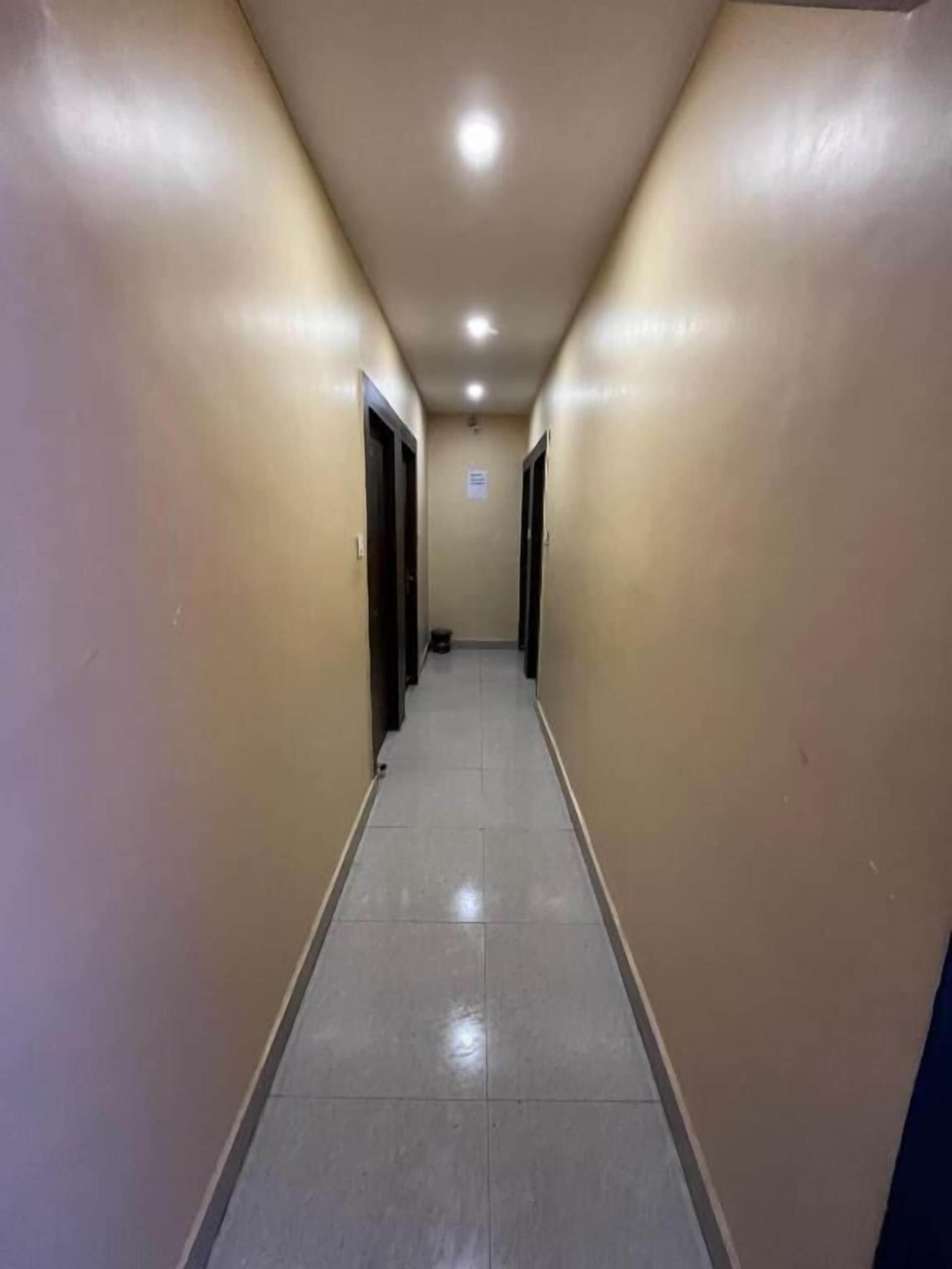 A narrow hallway with doors on both sides, leading to rooms.