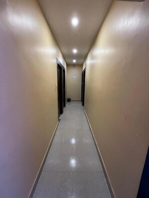 Un estrecho pasillo con puertas a ambos lados, que conduce a habitaciones.