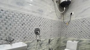 Een badkamer met een marmeren vloer, een wastafel, toilet en een douchehoek.
