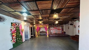 A spacious hall with a high ceiling, a stage with floral decorations, and a seating area.