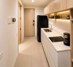 A modern kitchen with a black refrigerator, white cabinets, a stainless steel sink, and a coffee maker. - Suite with a private hot tub and ocean view (Magdalena)