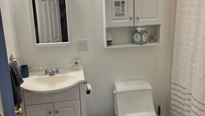 Un bagno con lavandino, specchio, servizi igienici e cestino.