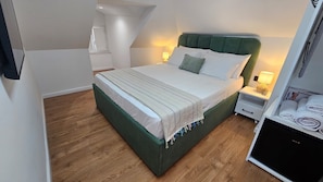 Un dormitorio con cama, mesitas de noche y un armario.