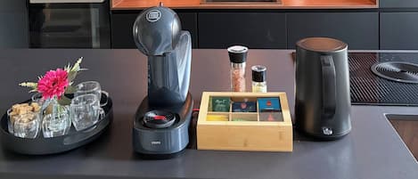 A modern kitchen with built-in appliances, a wooden shelf, and a coffee station.