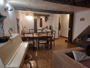 Zona d'estar acollidora amb taula de dinar, cadires, sofà i una banca.