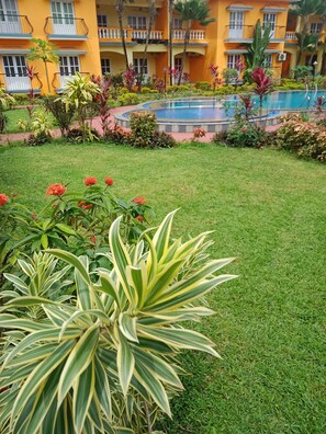 Ein Hotelinnenhof mit Schwimmbad, üppiger Bepflanzung und einem gepflegten Rasen.
